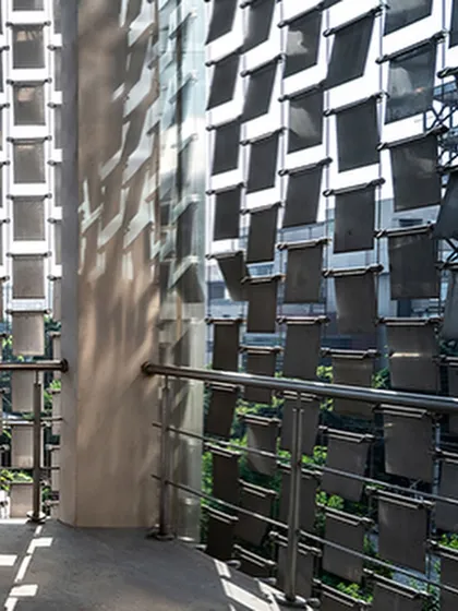 A detail shot of the 'shimmer screen,' showing how the individual steel panels are fixed to create a kinetic façade that casts moving shadows and reflects sunlight.
