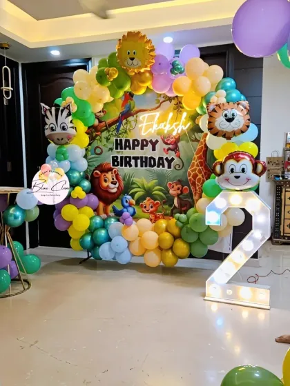 A full view of a jungle-themed second birthday, showing the circular backdrop, balloon garland, and marquee number.