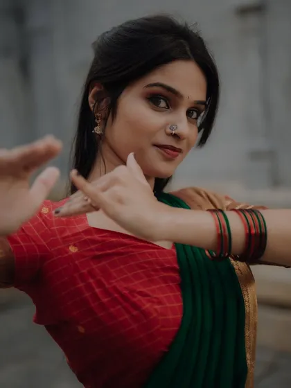 A close-up portrait capturing the expressive hand gestures, or mudras, of a classical dancer. The focus is on the details of her traditional attire and the emotion she conveys.