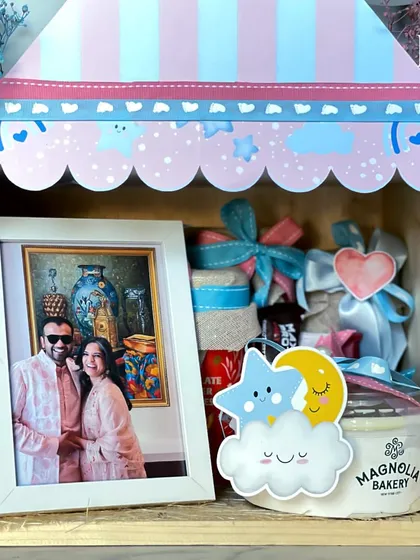 Inside the parents-to-be hamper, a photo of the happy couple sits next to a tub of Magnolia Bakery pudding and other thoughtful treats. It's a gift that celebrates their love story as they start a new chapter.
