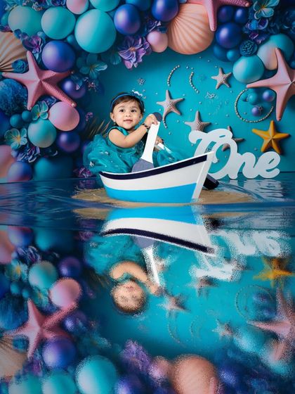 Sailing through a magical sea. This shot uses a boat prop and a stunningly detailed backdrop to create a captivating mermaid-themed photo with a realistic water reflection.