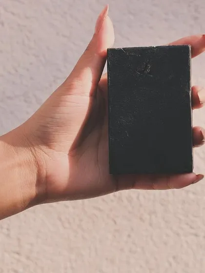 Elevate your bathing ritual with my Ultimate Detox Bar. This sleek, black soap is held here to show its simple, natural form. It's designed to deeply cleanse and purify your skin, leaving you feeling refreshed and renewed.