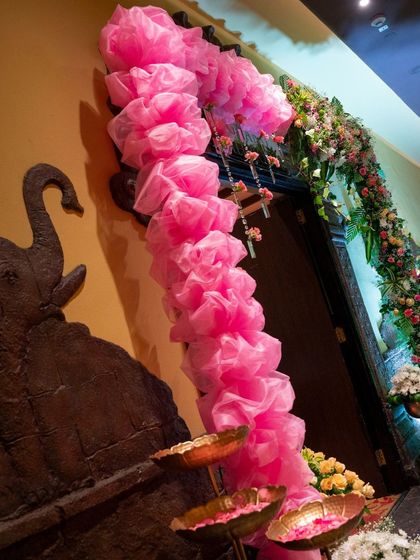 The entrance to the naming ceremony, featuring a pink fabric arch and floral arrangements that introduce the event's color scheme and theme right from the start.