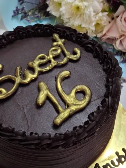 A rich and decadent dark chocolate cake I made for a Sweet 16 birthday. The cake is covered in smooth chocolate ganache and features elegant, handcrafted golden lettering for a sophisticated look.