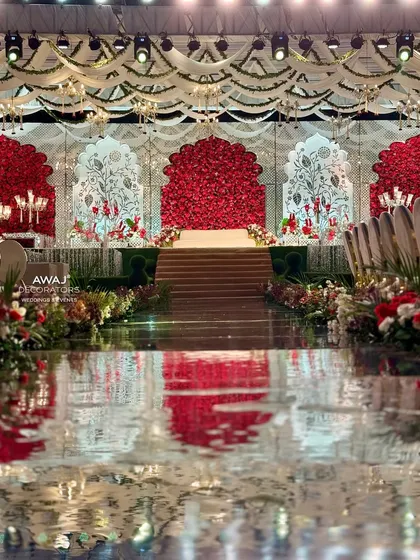 A closer view of the aisle leading to the stage, lined with lush red and white floral arrangements.