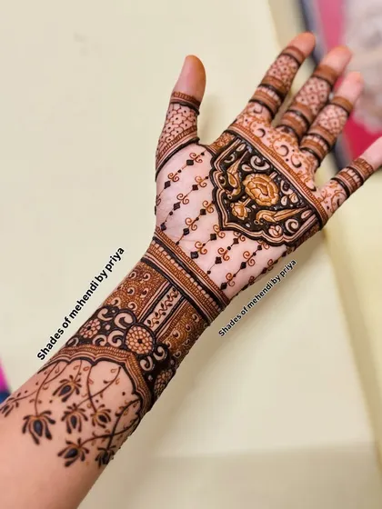 A side view of a bridal arm, showing how the design wraps around from the palm. The pattern includes floral elements and detailed cuff work.