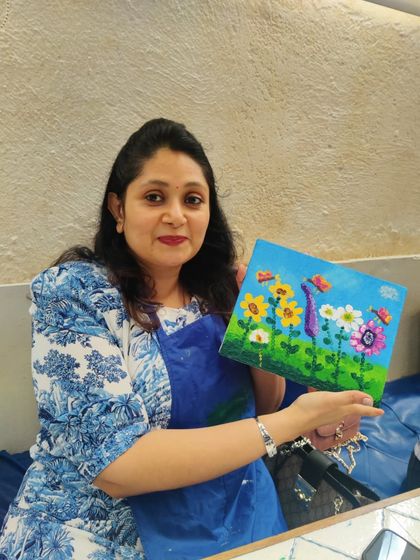 An adult guest at Nishka's birthday party proudly shows the colorful floral canvas she painted alongside the children.
