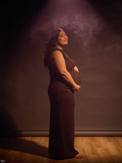 A solo portrait capturing the pure joy and anticipation of motherhood. The soft, hazy spotlight adds a dreamy, cinematic quality, focusing on her happy, sun-kissed expression.