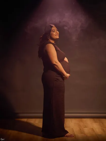 A solo portrait capturing the pure joy and anticipation of motherhood. The soft, hazy spotlight adds a dreamy, cinematic quality, focusing on her happy, sun-kissed expression.