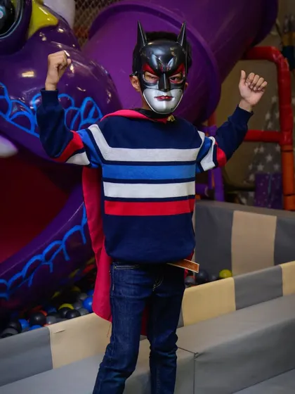 A young Batman strikes a power pose in front of the dragon slide.