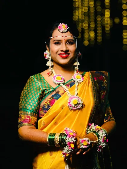 A beautiful smile from the bride-to-be. Here you can see the details of her floral necklace and jhumkas, designed to match her yellow and green saree perfectly.