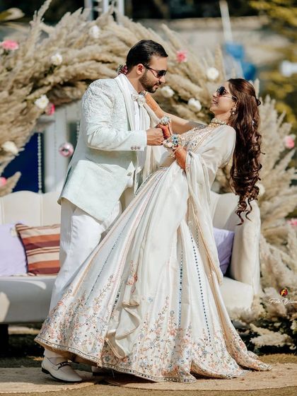 A beautiful dance pose during a sunlit Mehendi ceremony, with the couple looking elegant in their coordinated white outfits.