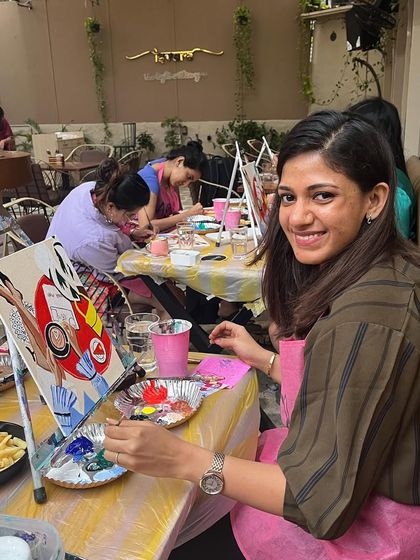 A participant enjoying her time at a cafe workshop, with her painting and some fries. It's a full sensory experience.