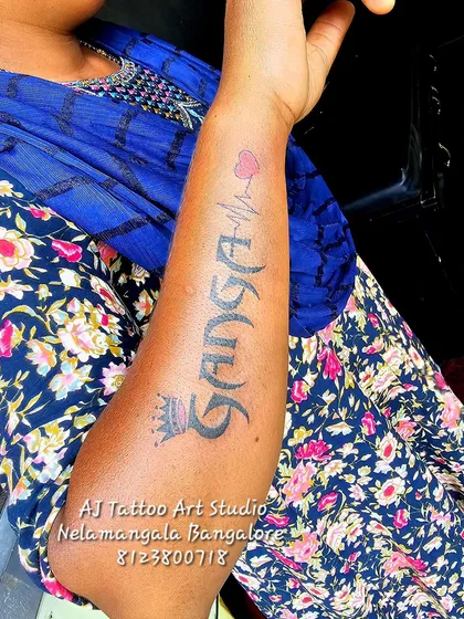 A "Ganga" name tattoo on the forearm with a crown and a heartbeat line.