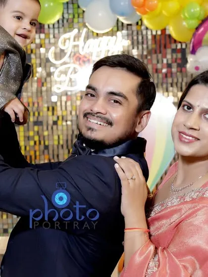 A proud father holds his son up for a happy family photo with mom. This candid shot captures the joy of the first birthday celebration.