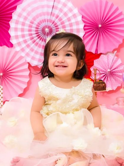 A radiant smile from the birthday girl, dressed in a beautiful cream-colored dress, surrounded by pink decorations.