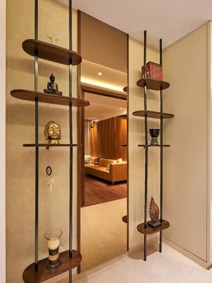 This entryway partition uses open shelving to create a sense of separation without blocking light or views. It serves as a display for personal artifacts, adding a touch of personality right at the entrance.