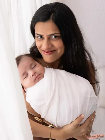 A mother's proud smile as she holds her sleeping newborn. These first portraits as a new mom are incredibly special and emotional.