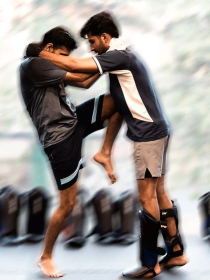 Two fighters locked in a clinch, drilling knee strikes and control techniques.