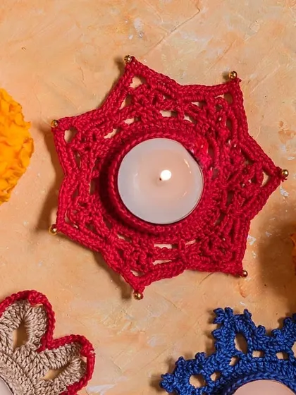 A collection of our star and flower-shaped crochet diya holders in red, blue, and beige. Mix and match different designs to create a vibrant festive display.