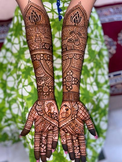 A full view of the romantic portrait mehandi, showing how the design extends up the arms with traditional elements like the dholak and lotus motifs.