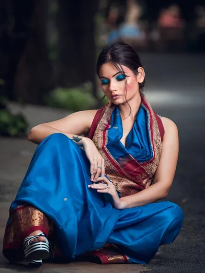 An urban-ethnic fusion shoot, pairing a traditional saree with modern platform heels. The street setting and bold blue makeup create a unique and contemporary fashion statement.