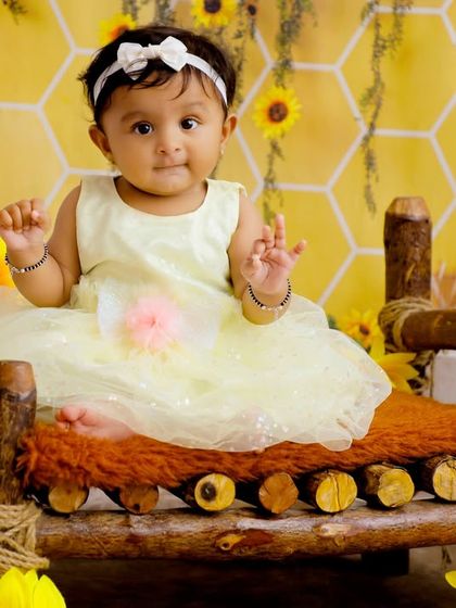 A sweet baby girl sitting on a rustic wooden bed in our honeycomb and sunflower set. The warm lantern light adds a magical touch to this enchanting portrait.