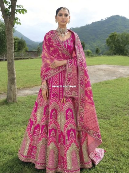 The full glory of the pink bridal lehenga is on display here, showing the rich fabric, intricate weaving, and the beautiful way the dupatta drapes.