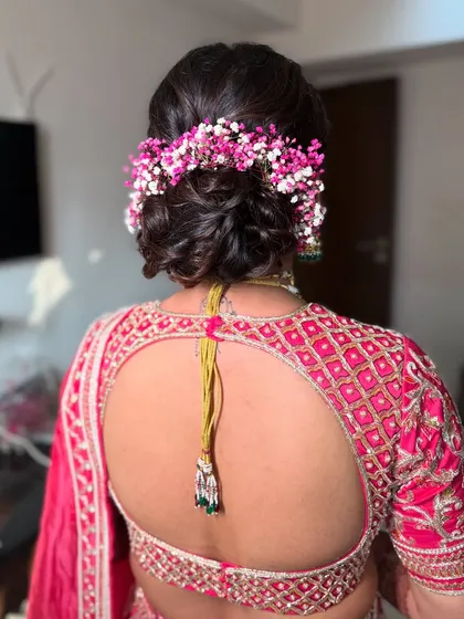 A closer look at the textured messy bun with colorful pink and white gypsy flowers. This style adds a touch of playful elegance to any festive occasion.