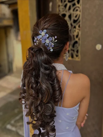 Hairstyling is just as important as makeup. Here, I’ve created a voluminous, textured ponytail with soft curls, accented with custom floral pieces that perfectly match the client's lavender outfit, ideal for a chic reception look.