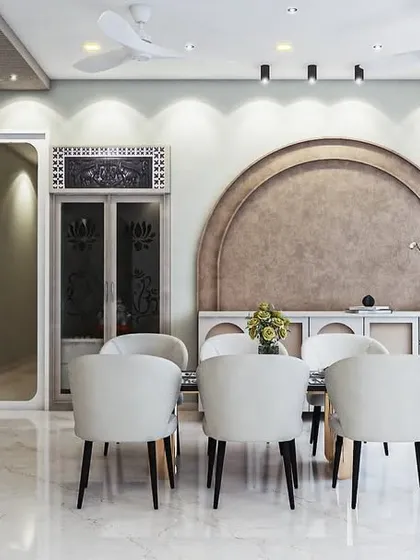 This dining area design uses an arched, textured feature wall to create a soft, organic focal point. Paired with simple white chairs and subtle track lighting, the space feels elegant, modern, and calming.
