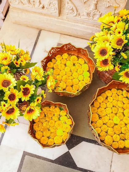An overhead shot of decorative bowls filled with floating marigolds and sunflowers, a beautiful and traditional element of Indian wedding decor.