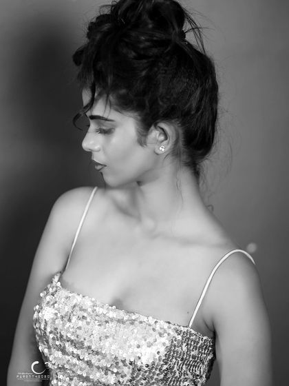 A pensive and elegant portrait in black and white. The messy updo and her downward gaze create a moody and artistic feel.
