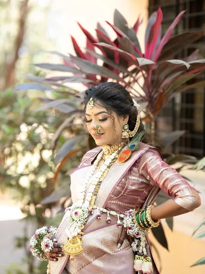 A candid shot of a mom-to-be during her Dohale Jevan, wearing a custom floral set with a prominent 'Aai' brooch.
