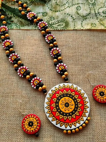 A full view of the red and white mandala 'haram' style necklace, complete with its matching earrings.