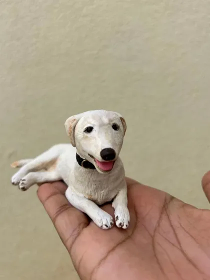 A custom dog miniature, resting in my hand. Each one is sculpted from polymer clay based on your photos. I take great care to get the details just right.
