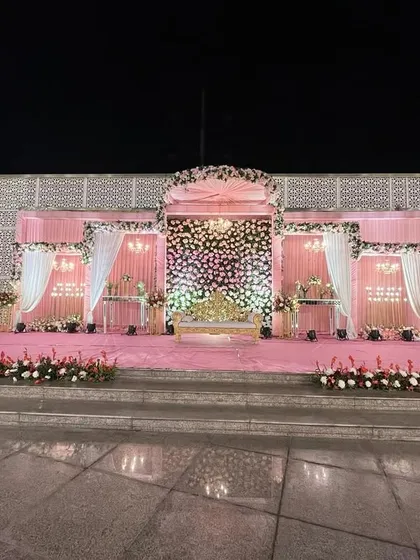A grand stage setup with a pink and white floral design. The symmetrical layout and beautiful lighting make it a perfect centerpiece for a large reception.