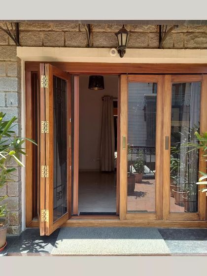 Large, foldable wooden doors open up a room completely to a balcony, erasing the boundary between inside and out.