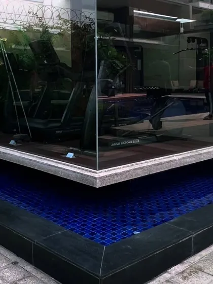A modern gym with floor-to-ceiling glass walls appears to float over a water channel that connects to the main pool, blending fitness and relaxation.