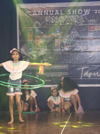 Our younger students having fun with hula hoops on stage, a playful and engaging performance.