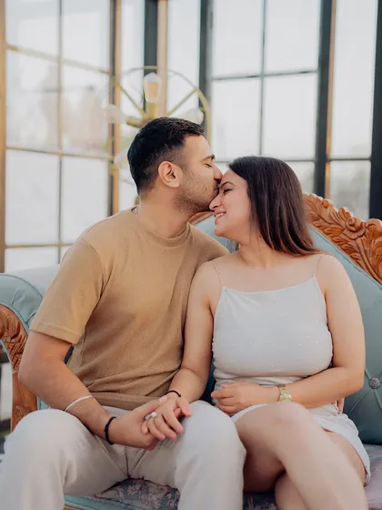 A close-up of a tender forehead kiss, showcasing the couple's affection in the soft, natural light of the conservatory.