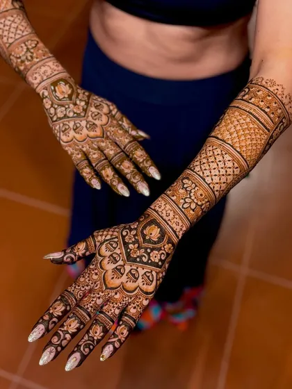 A full-arm bridal design with a beautiful mix of bold and fine lines. The pattern includes traditional Indian motifs that flow from the palm to the elbow, creating a striking look for any bride.