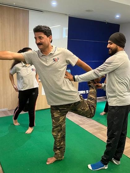 Another hands-on assist during a corporate wellness class. This helps employees understand the alignment of balancing poses like Natarajasana (Dancer's Pose).