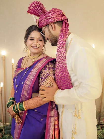 A sweet, candid moment between the bride and groom. Her makeup in shades of purple and pink complements her violet saree beautifully.