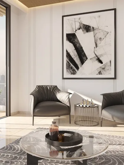 A clean, bright seating area featuring modern leather armchairs and a glass coffee table. The design uses white fluted wall panels and a large abstract art piece to create a sophisticated and light-filled corner, perfect for conversation.
