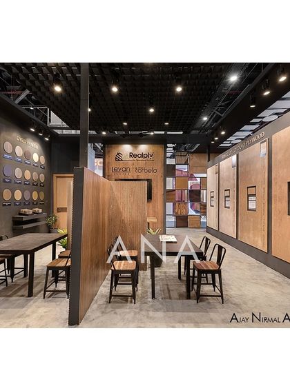 A long view of the Realply '23 interior, highlighting the organized layout of discussion tables and extensive product walls. The dark ceiling and track lighting create a focused, gallery-like atmosphere.