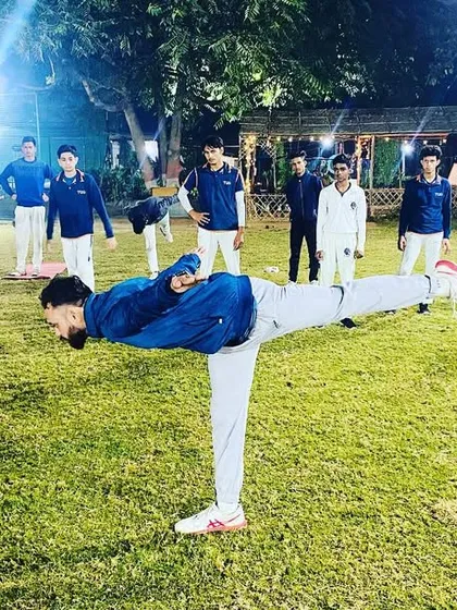 A player demonstrates excellent balance during a stretching exercise, with a coach leading the group. We teach our athletes to control their bodies.