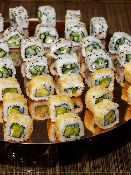 We believe in culinary artistry. This platter of freshly prepared avocado and cucumber sushi rolls showcases our commitment to beautiful presentation and high-quality ingredients for our global cuisine offerings.
