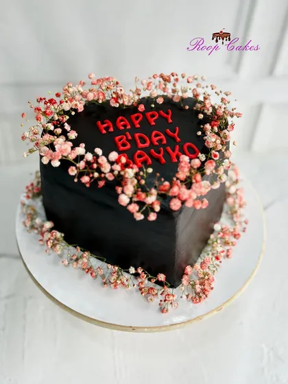 A bold and romantic cake for a "Happy B'day Bayko." This striking black heart-shaped cake is made with rich chocolate truffle and decorated with delicate baby's breath, showing how a simple design can make a powerful statement of love.