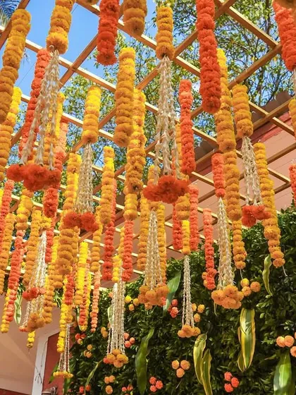 A ceiling of hanging marigold garlands creates a breathtaking canopy of color and fragrance, completely transforming the event space.